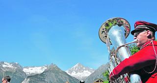 Gebl&auml;se. Musikant der MG &laquo;Illhorn&raquo; mit Blick f&uuml;r seine Tuba. Hinten majest&auml;tisch das 3934 Meter hohe Bietschhorn. 