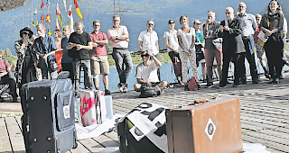 Liegen gebliebene Koffer. Kunstschaffende, Verantwortliche sowie Kulturinteressierte und Staatsr&auml;tin Esther Waeber-Kalbermatten (ganz rechts): Sie h&ouml;rten bei der Autobahnrastst&auml;tte gespannt den Informationen der Kuratoren zu.