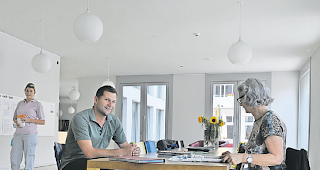 Gemeinschaftsraum. Direktor Daniel Kalbermatten am Tisch im Gemeinschaftsraum im Parterre mit einer Besucherin: &laquo;Ich erwarte eine für den Betrieb und in der Qualit&auml;t optimale L&ouml;sung.&raquo;