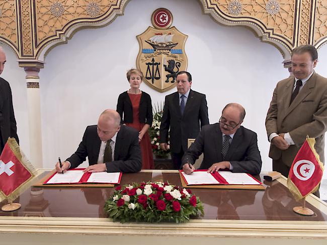 Vincenzo Mascioli, Vizedirektor im Staatssekretariat für Migration (l.) und Mohamed Ali Nafti, Generaldirektor für konsularische Angelegenheiten, unterzeichnen die neue Kooperationsstrategie Schweiz-Tunesien. Dahinter stehen Bundesrätin Simonetta Sommaruga und Aussenminister Khemaies Jhinaoui.