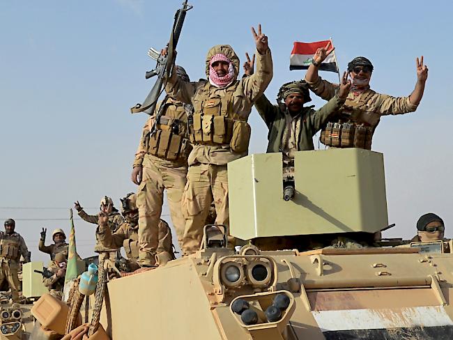 Irakische Einheiten mit Flaggen und Siegeszeichen. Das Land braucht nun Geld zum Wiederaufbau. (Archiv)