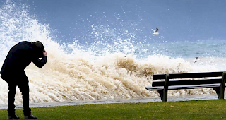 Ein Mann duckt sich vor der Gischt.