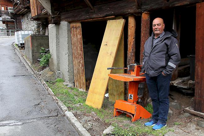 Michael Meyer vor seinem Stadel in Kippel. Neben ihm die Spaltmaschine.