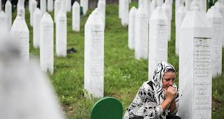Eine trauernde Frau zwischen Grabsteinen einer Gedenkst&auml;tte in Srebrenica