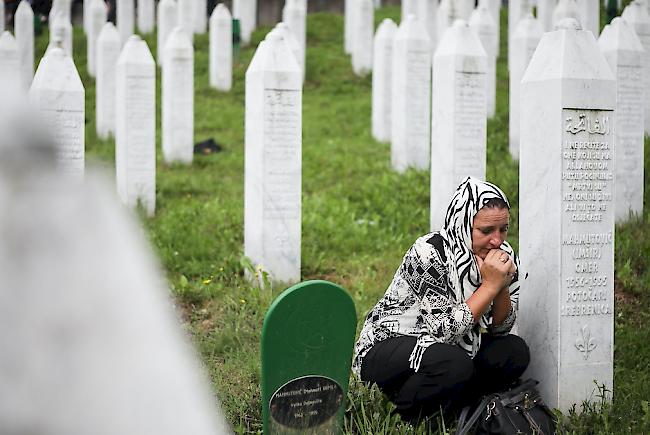 Eine trauernde Frau zwischen Grabsteinen einer Gedenkstätte in Srebrenica