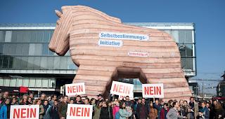 Personen demonstrieren mit Plakaten und einem Trojanischen Pferd gegen die Selbstbestimmungsinitiative der SVP.