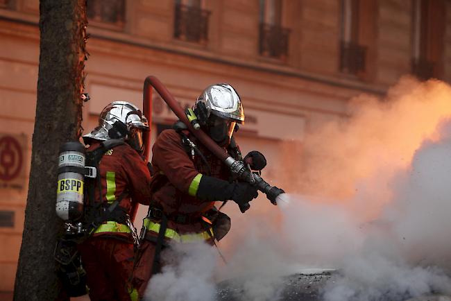 Feuerwehrleute versuchen ein brennendes in der Nähe der Pariser Prachtstrasse Champs-Élysées zu löschen. 

