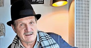 Kreativer Kopf mit Hut. Kurt Regotz mit einer Skizze und der fertigen Karikatur zum World Nature Forum und seinen Rettern, wie sie demn&auml;chst in der &laquo;R&auml;tscha&raquo; erscheint.