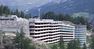 Das 1980 beim Dorfeingang von Saas-Fee erbaute Parkhaus P3 (links) muss saniert werden weil unter anderem die Parkfl&auml;chen &uuml;ber kein Oberfl&auml;chenschutzsystem verf&uuml;gen. 