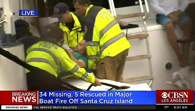 Behörden helfen einem Mann, der aus dem tödlichen Bootsbrand gerettet wurde. (TV-Bild)