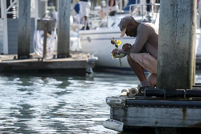 Ein Betroffener hält Blumen in der Hand und nimmt sich einen Moment Zeit, um an einem Dock in Santa Barbara nachzudenken.