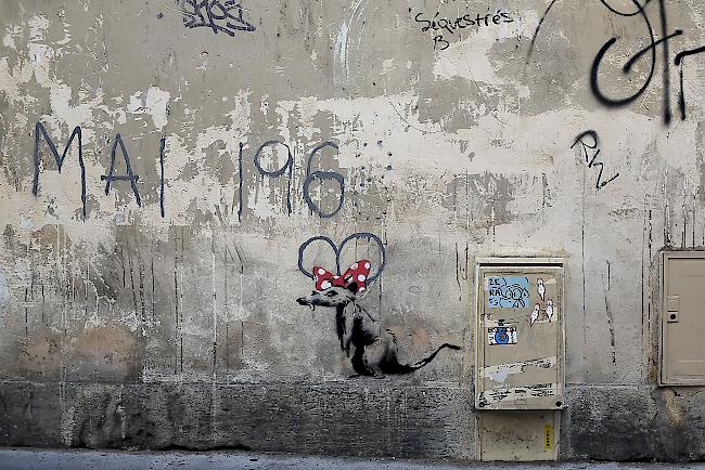 An einer Wand entlang einer Strasse in Paris ist eine Ratte mit einer roten Schleife zu sehen, die vermutlich dem Strassenkünstler Banksy zuzuschreiben ist. (Symbolbild)