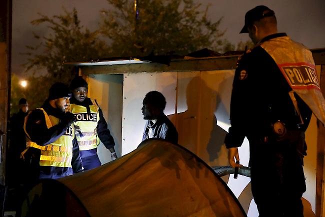 Französische Polizeibeamte evakuieren am Donnerstag einen Migranten während einer grossen Operation zur Räumung provisorischer Migrantenlager.