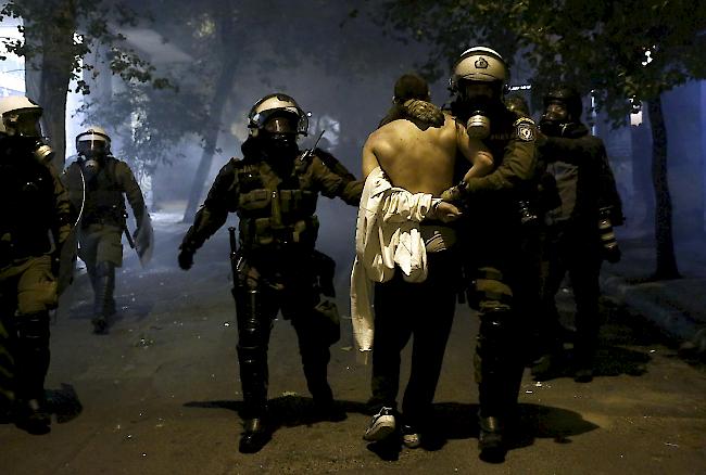 Ein Demonstrant wird nach Zusammenstössen während einer Demonstration zum elften Jahrestag der Ermordung des Teenagers Alexis Grigoropoulos im Zentrum von Athen festgenommen.
