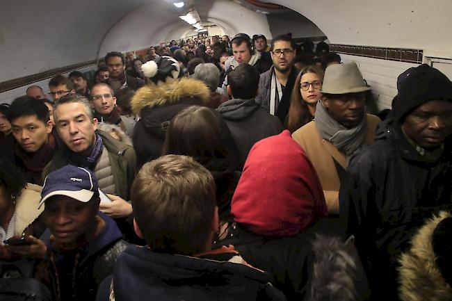 Pendler warten in Paris an einem Bahnsteig auf eine U-Bahn.