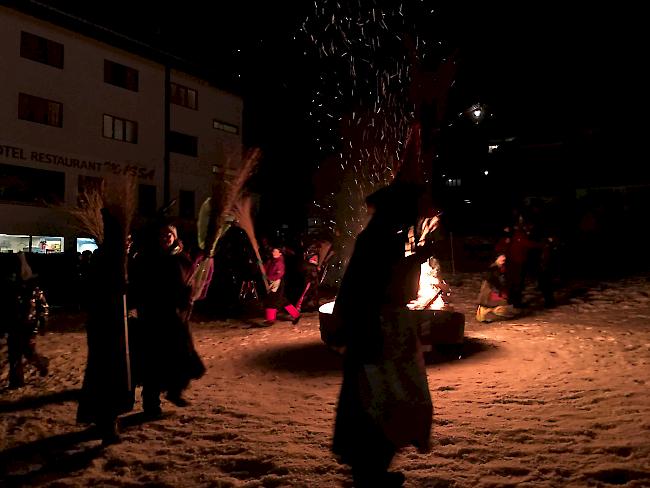 Kinder und ihre Eltern tanzten am Freitag mit Hexenbesen ums Feuer in Blatten, begleitet von heiteren Guggenmusik-Klängen.