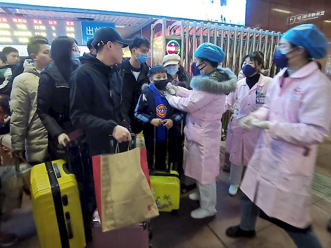 Medizinische Personal misst bei Zugspassagieren in Yingtan City in der Provinz Jiangxi die Temperatur.