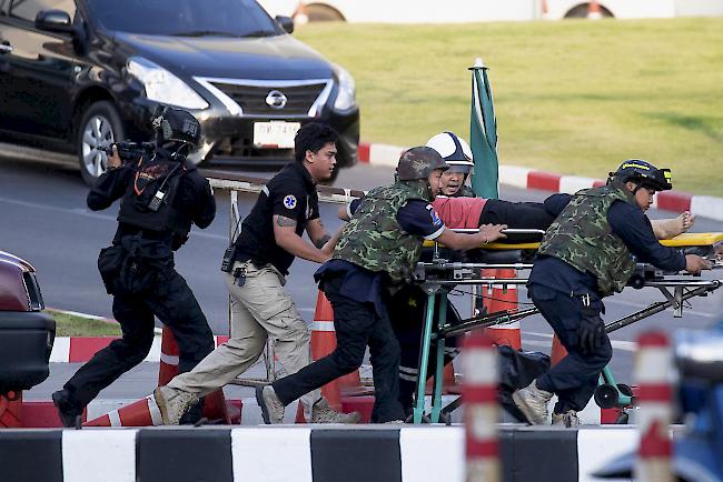 Bewaffnete Kommandosoldaten tragen eine Person aus dem Korat-Einkaufszentrum im Terminal 21 in Nakhon Ratchasima, Thailand.