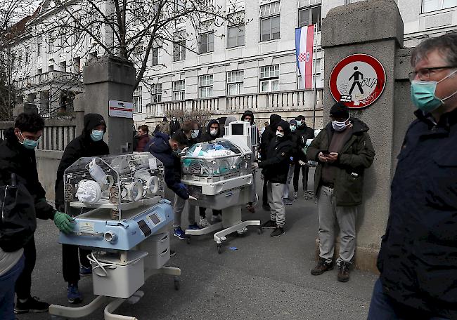 Menschen tragen nach dem Erdbeben in Zagreb, Kroatien, Inkubatoren für Neugeborene aus einem Krankenhaus.