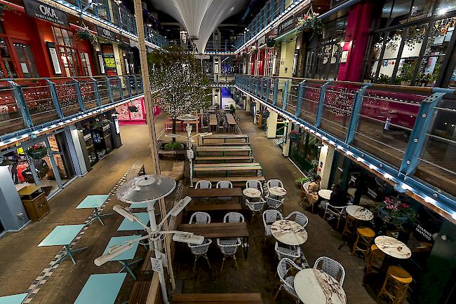 Ein Paar sitzt an einem Tisch in einem geschlossenen und leeren Food Court in der Gegend von Soho in London, Grossbritannien.